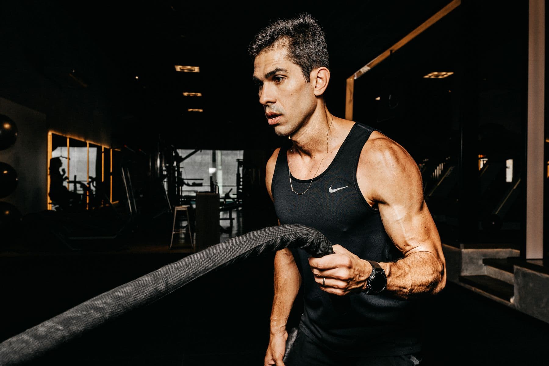 Athlete training with battle ropes in a dark gym